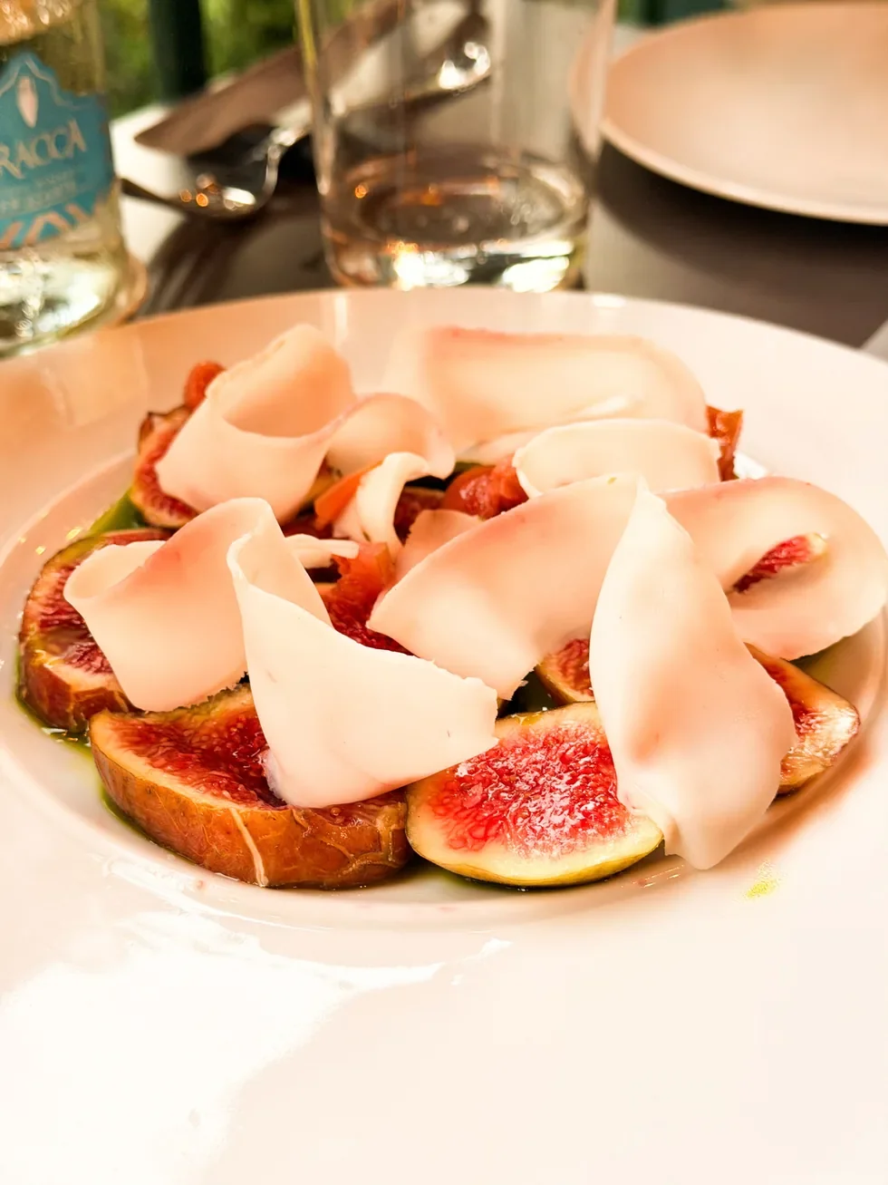 Dojrzałe figi z cienkimi plastrami słoniny lardo na talerzu w restauracji w Bergamo